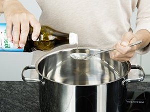 Eine Person gibt Speiseöl in einen Topf.