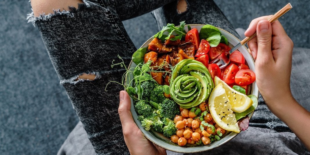 Eine Person von oben fotografiert hat eine Gabel und einen Teller mit einer Bowl auf dem Schoß... Artikel "Vege...-was?" öffnen.